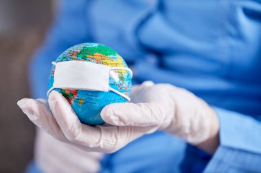 Doktor dünyayı koruyucu maskeyle tutuyor.