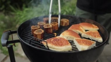 Elinde maşa tutan ve et parçalarını ızgaraya çeviren adamın yakın görüntüsü  