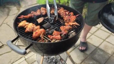 Elinde maşa tutan ve et parçalarını ızgaraya çeviren adamın yakın görüntüsü  