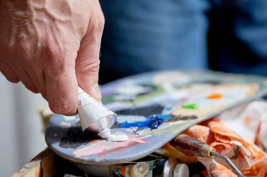 Ressam palette tüpten boya sıkıyor, yakın görüş