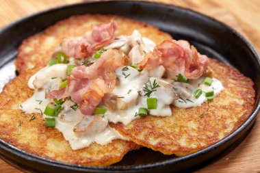 Ekşi kremalı patates gözlemesi ve tavada domuz pastırması, ahşap kesim tahtası, yakın görüş. 