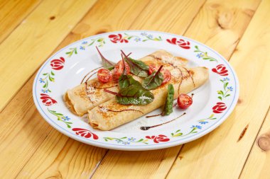 Beyaz tabağa doldurulmuş jambonlu ve peynirli dürüm. 