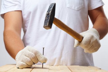 Kapalı alanda tahta çivi çakan adam, yakın görüş.