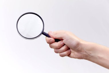 Beyaz arka planda büyüteç tutan erkek eli.