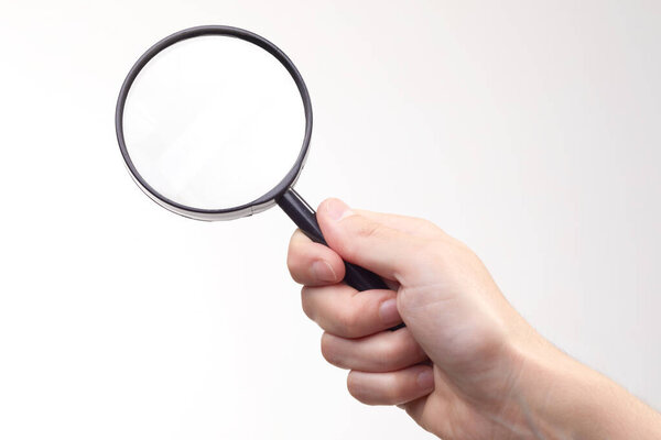 Closeup of male hand holding magnifying glass on white background