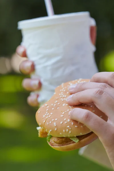 Žena jíst hamburger a koktejl — Stock fotografie