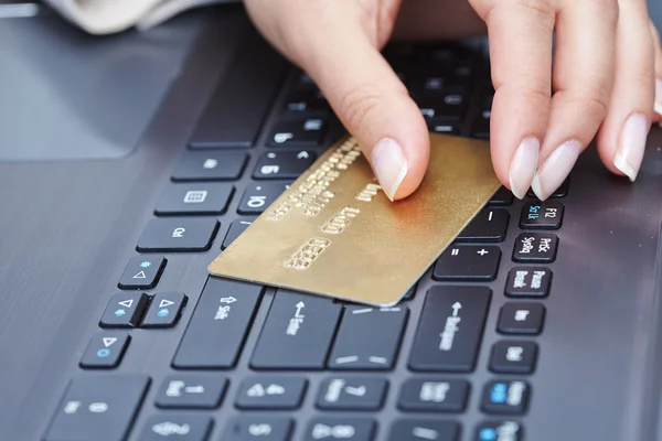 Mujer sosteniendo tarjeta de crédito en el ordenador portátil — Foto de Stock