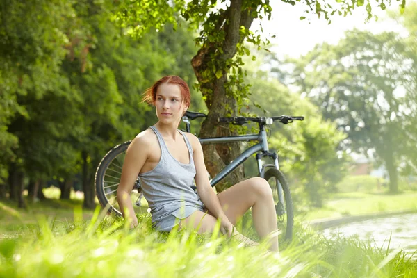 Kobieta zielony trawnik w pobliżu rower — Zdjęcie stockowe