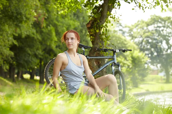 Женщина сидит рядом с велосипедом — стоковое фото