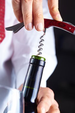 Adam şarap şişesini açıyor.