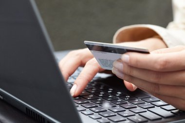 kredi kartı laptop üzerinde tutan kadın