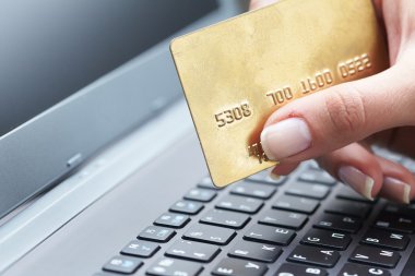 kredi kartı laptop üzerinde tutan kadın