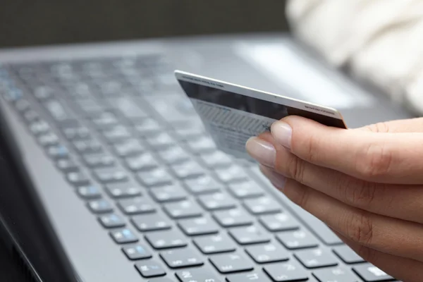 Mujer sosteniendo tarjeta de crédito en el ordenador portátil —  Fotos de Stock