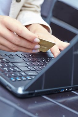 kredi kartı laptop üzerinde tutan kadın