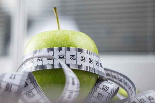 Яблоко с измерительной лентой — стоковое фото