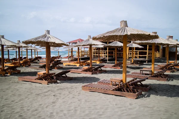 Houten parasols met stoelen op strand — Stockfoto