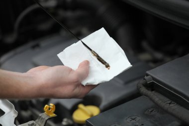 Auto mechanic checking engine oil dipstick in car