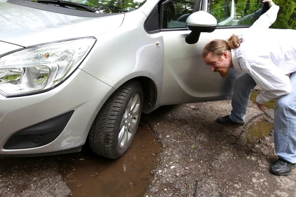 Coche dañado de la carretera llena de baches agrietados en el pavimento — Foto de Stock