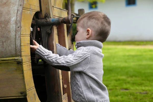 2 år gammal nyfiken pojke hantera med gamla jordbruks mach — Stockfoto