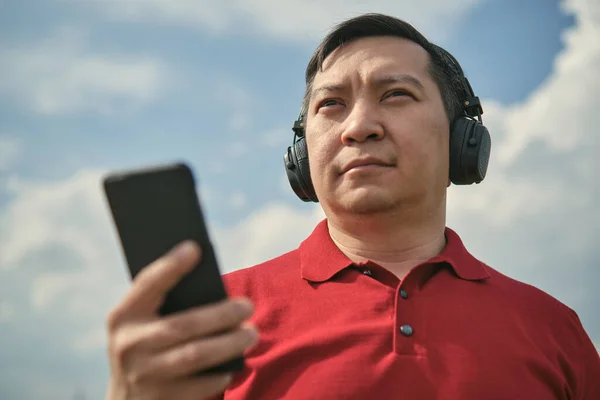 Middelbare Leeftijd Aziatische Man Hoofdtelefoon Buiten Luisteren Naar Muziek Tegen — Stockfoto