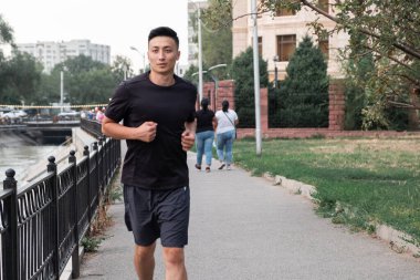 Şehirde koşan Asyalı bir adam, akşam vakti. Kazakistan