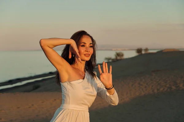 落日的时候 一个穿着苍蝇白色衣服的女孩在沙漠里跳舞和摆姿势 — 图库照片