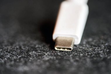 Yakından bakıldığında, beyaz bir USB-C konnektörünün karanlık bir yüzeyde dinlendiğini görüyoruz. Odaklanma konnektörün sonunda, detaylarını vurguluyor.