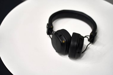 Siyah kulaklıklar temiz beyaz bir yüzeyde duruyor. Reklam teknolojisi, ses ve yaşam tarzı kavramları için uygundur.