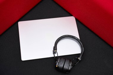 Temiz ve minimalist çalışma alanı düzeneği gümüş dizüstü bilgisayar, kulaklık ve koyu kırmızı arka plan. Yaratıcı tasarım veya iş temaları için ideal