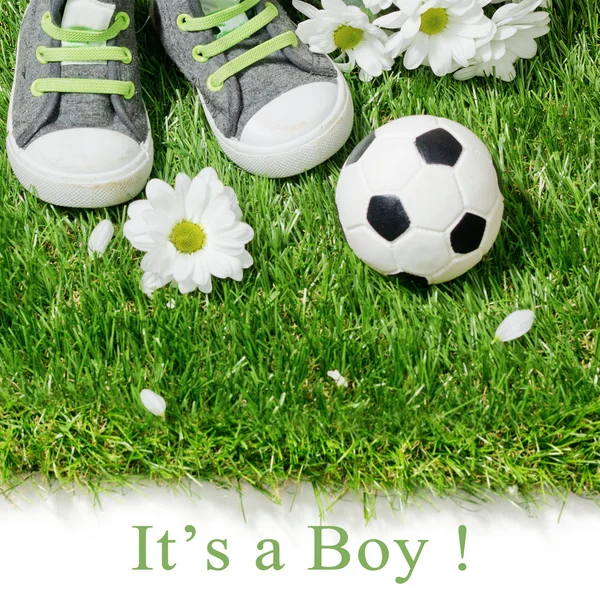 Jungenschuhe und ein Fußballball auf dem Rasen. Konzept für Baby — Stockfoto