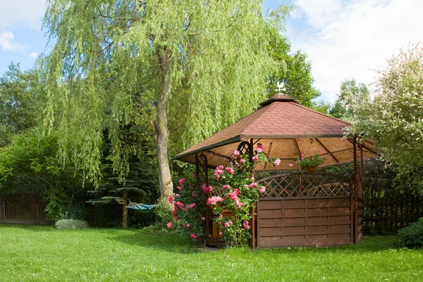 Gazebo esterno in legno con rose e sfondo del paesaggio estivo — Foto Stock