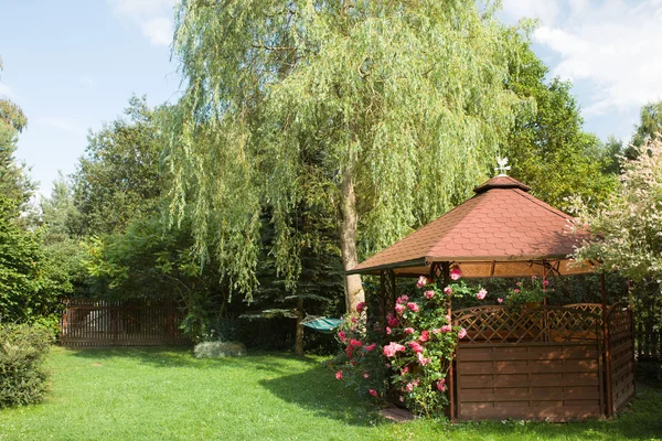 Gazebo esterno in legno con rose e sfondo del paesaggio estivo — Foto Stock