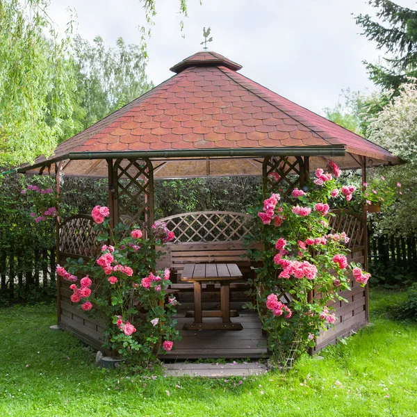 Drewniana altana na zewnątrz z różami i letnim tłem krajobrazowym — Zdjęcie stockowe