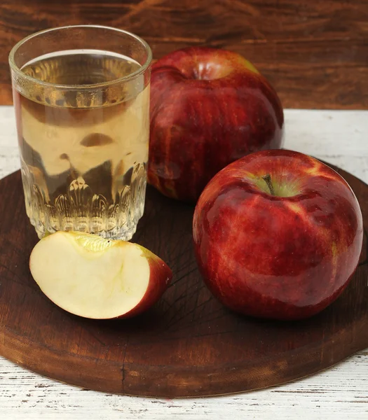 Κόκκινα μήλα και χυμό μήλων σε ξύλινο τραπέζι — Φωτογραφία Αρχείου