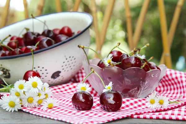 Sweet cherries on a wooden table in the garden — Stock Photo, Image