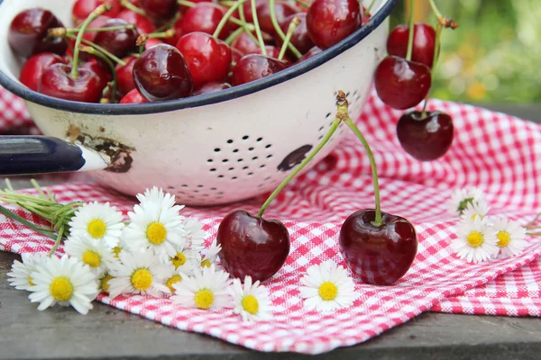 Sweet cherries on a wooden table in the garden — Stock Photo, Image
