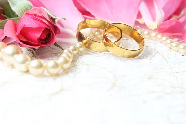 Paar van huwelijksringen met rozen voor achtergrondafbeelding — Stockfoto