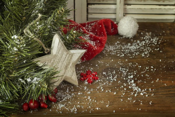 Fir kerstboom met red hat en sneeuw op een houten achtergrond — Stockfoto