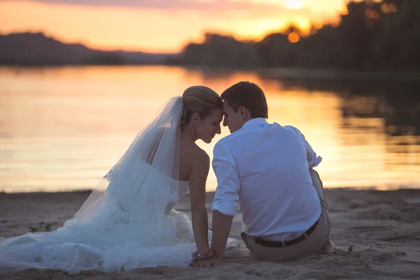 Молодая супружеская пара на реке с закатом — стоковое фото