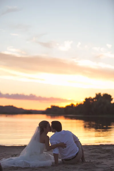 Coppia appena sposata sul fiume con tramonto — Foto Stock