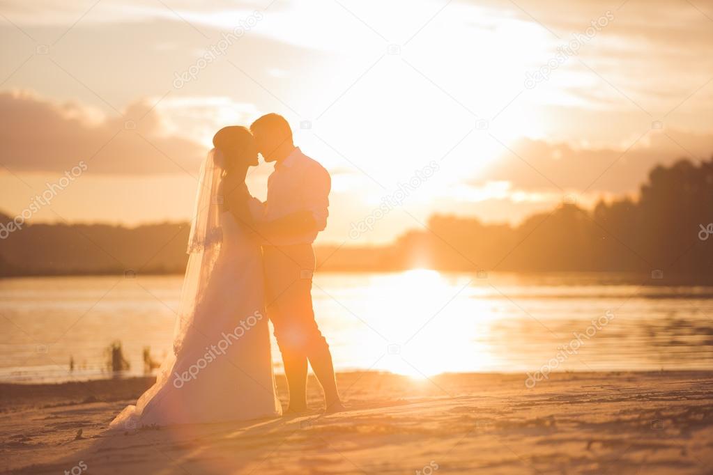 Newly married couple on the river with sunset