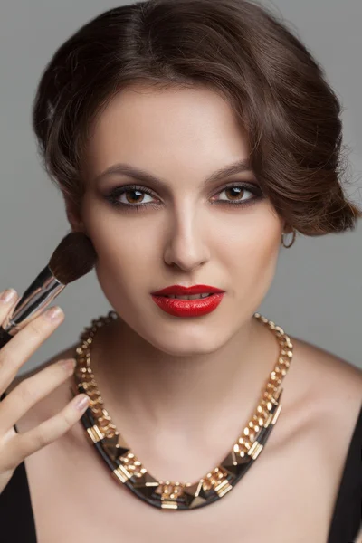Hermosa mujer con maquillaje de noche rodeada de los diferentes cepillos para maquillar —  Fotos de Stock