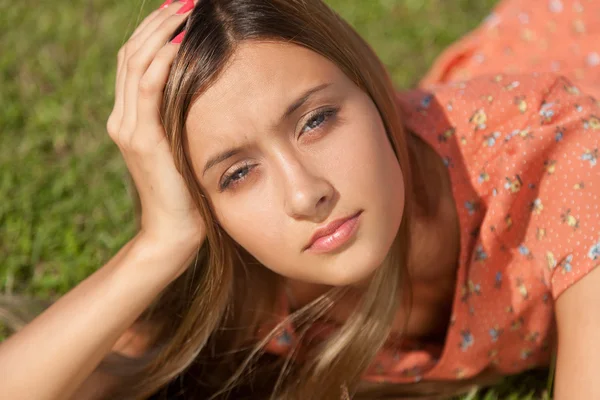 Beautiful girl lying on the grass and smiling while looking at the camera — Stock Photo, Image