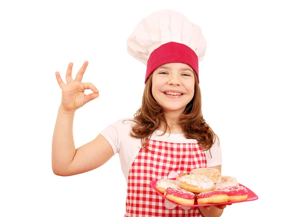 Щаслива маленька дівчинка готує з пончиками та значком для рук — стокове фото
