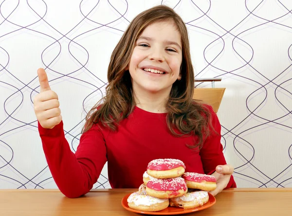 Šťastná holčička s sladké koblihy a palec nahoru — Stock fotografie