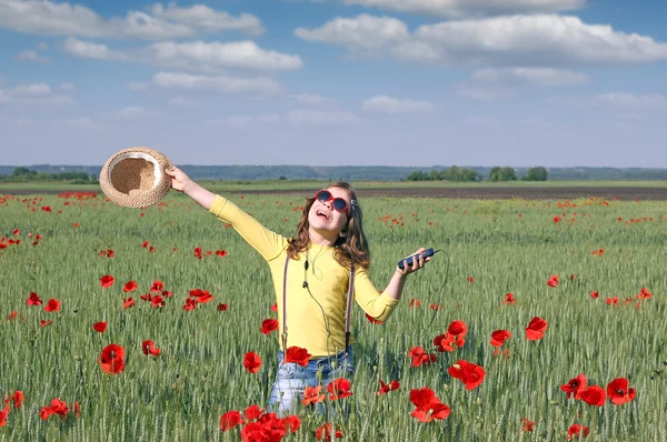 Fröhliches kleines Mädchen hört auf der Wiese Musik am Telefon — Stockfoto