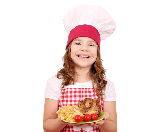Happy little girl cook with roasted chicken wings on plate — Stock Photo, Image