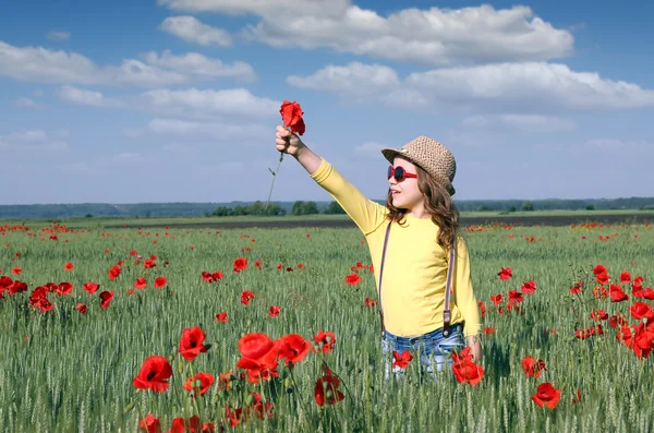 Bonne petite fille avec des fleurs de pavot sur la prairie — Photo