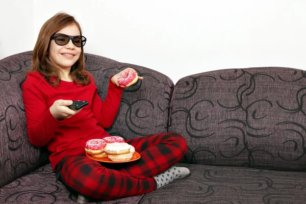 Menina com óculos 3d assistindo tv e comer donuts — Fotografia de Stock