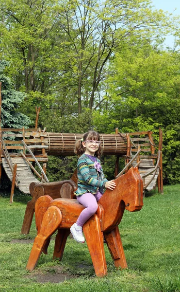 Heureuse petite fille chevauchant cheval en bois — Photo